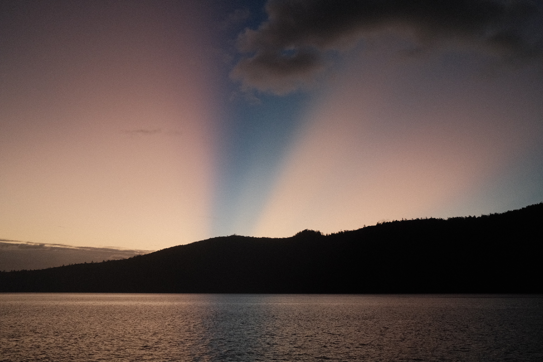 Twilight over a coastal inlet in Noosa, crepuscular light behind a dark headland